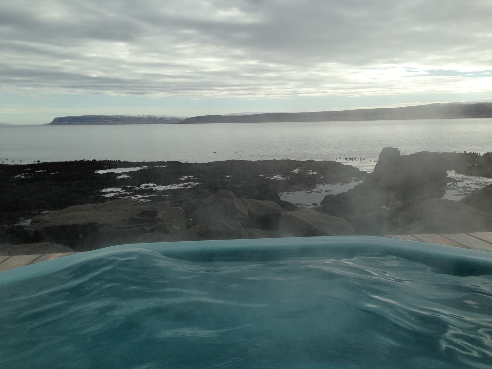 View from a Drangsnes shoreline hot tub across Steingrímsfjörður in cloudy weather.
