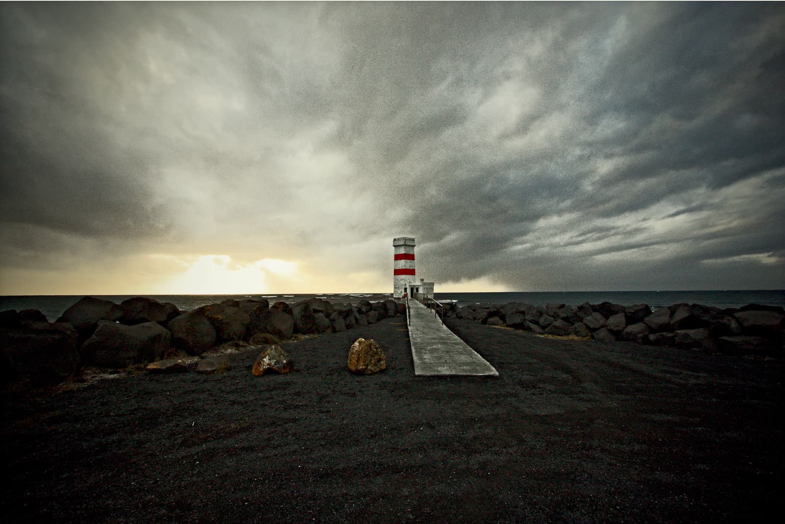 The old red-and-white Garðskagi lighthouse beside the low Reykjanes coast.