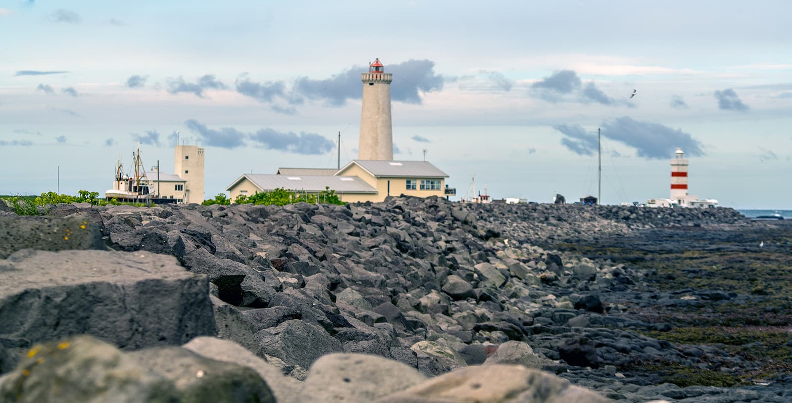 The old and newer Garðskagi lighthouses standing apart on the Reykjanes shoreline.