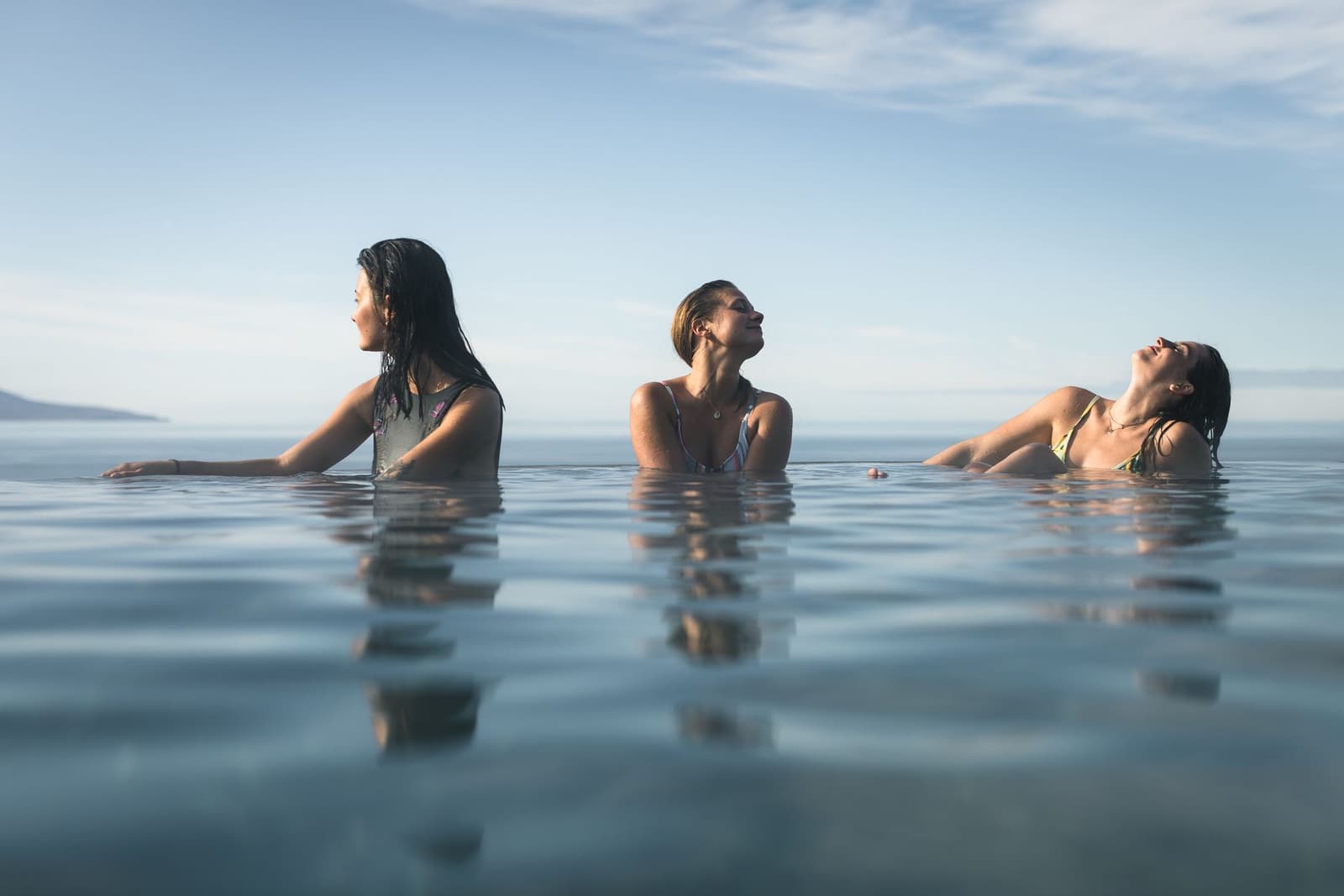 GeoSea geothermal seawater pool with clear water, steam, and Skjálfandi Bay in the background.
