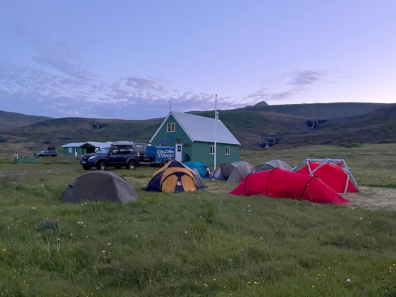 Green hut, tents, and open slopes in the Vöðlavík hiking area near Gerpir.