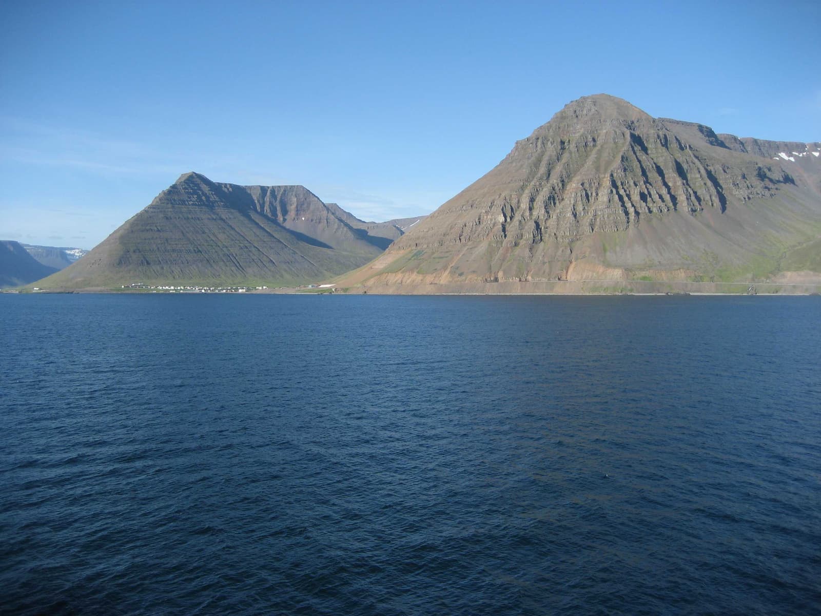 Hnífsdalur seen across the water beneath the cliffs near Óshlíð in the Westfjords.
