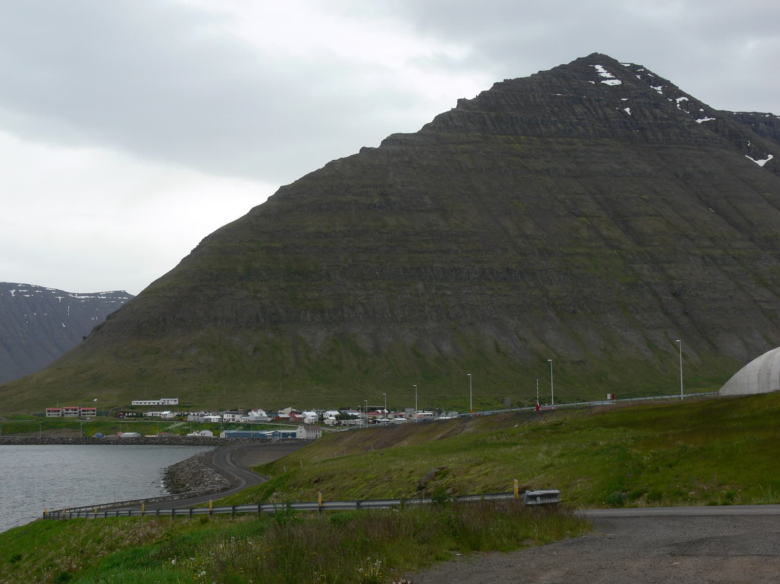 Road and tunnel approach beside steep mountain walls at Hnífsdalur in the Westfjords.