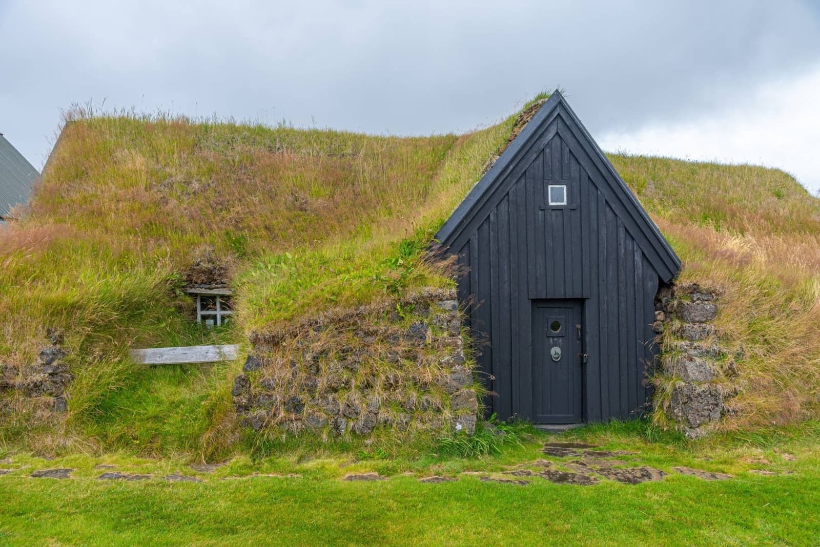 Keldur Turf House near Hvolsvollur with turf roofs and open South Iceland farmland.