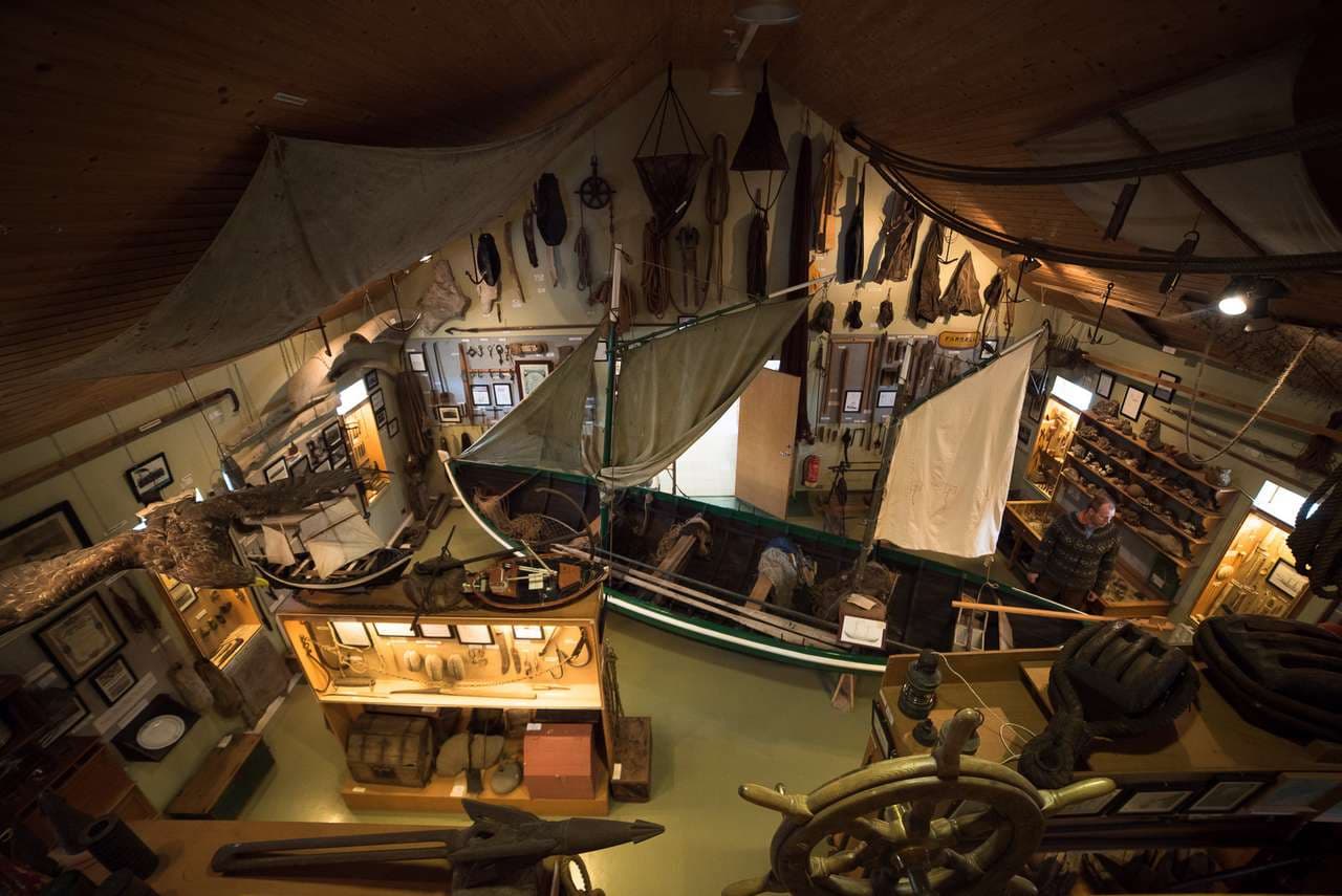 Interior of Hnjótur Museum with fishing and rural-life objects displayed around an old boat.