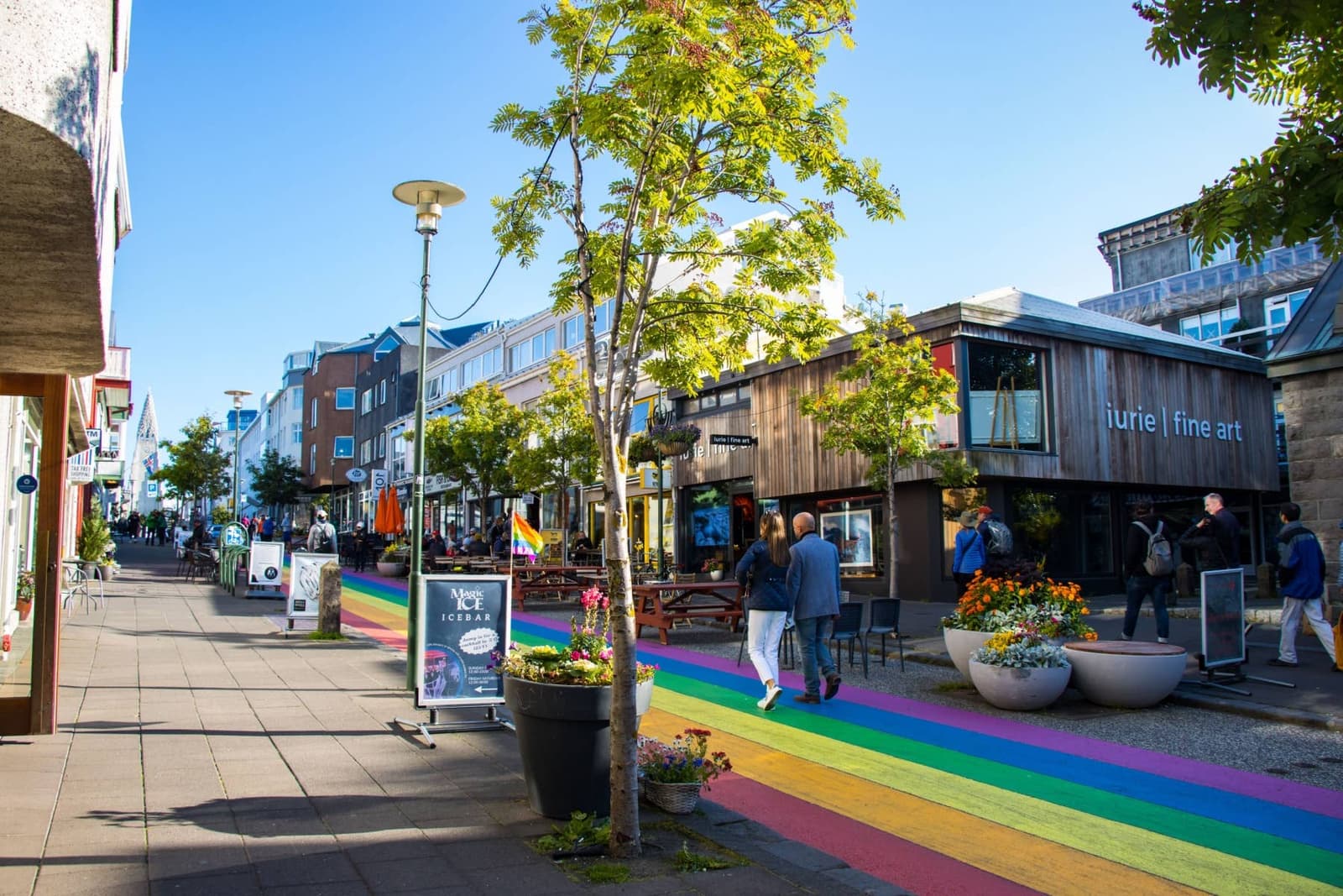 People walking beside shops and cafe seating on Skólavörðustígur Rainbow Street in Reykjavík.