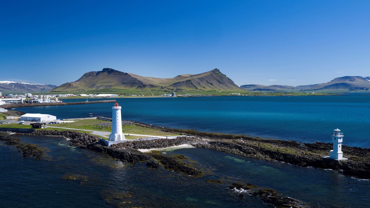 Akranes lighthouses on the coast with Akrafjall mountain rising behind the town in West Iceland.