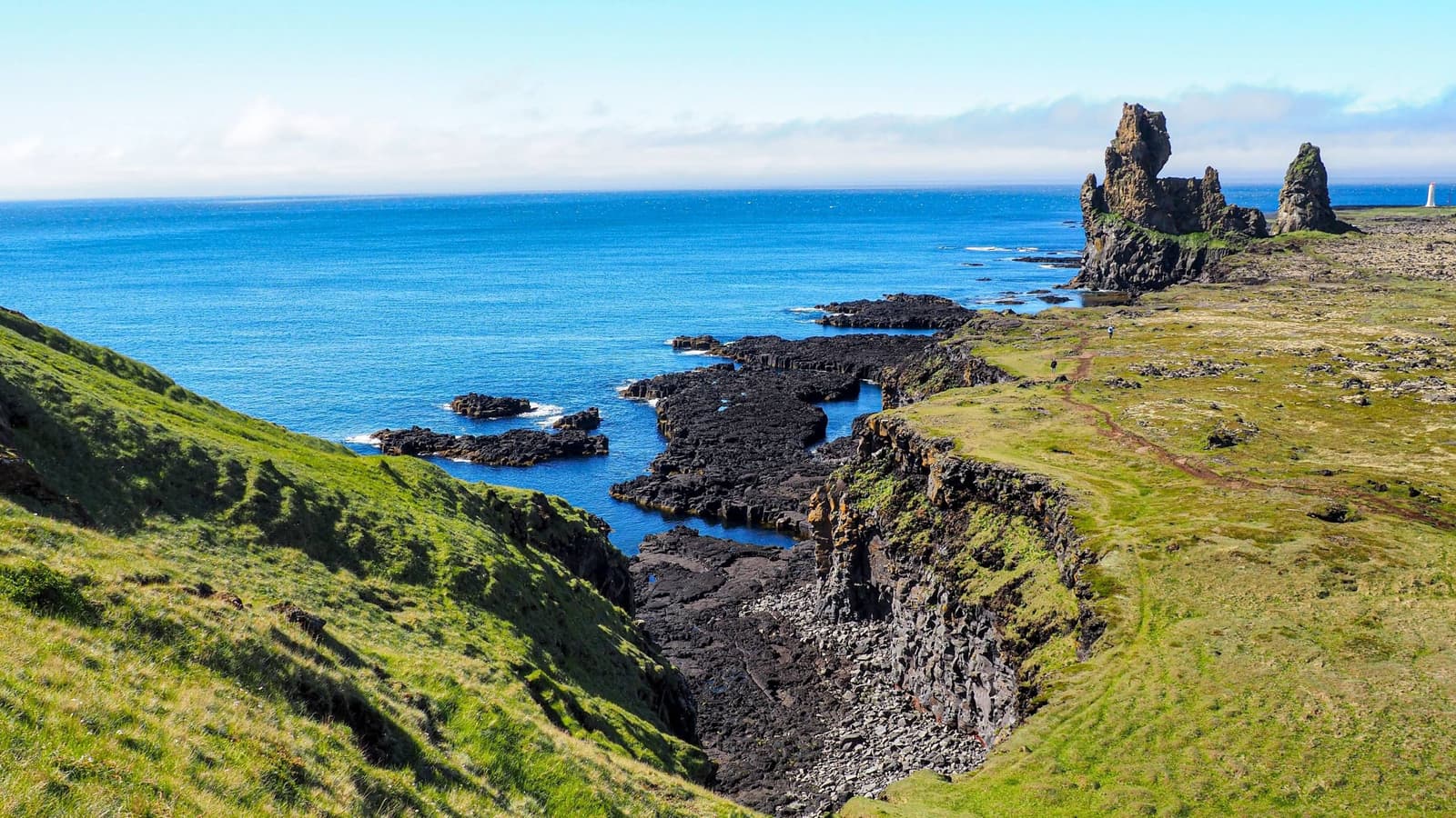 Arnarstapi coastal cliffs with sea stacks and a walking viewpoint above the Atlantic.