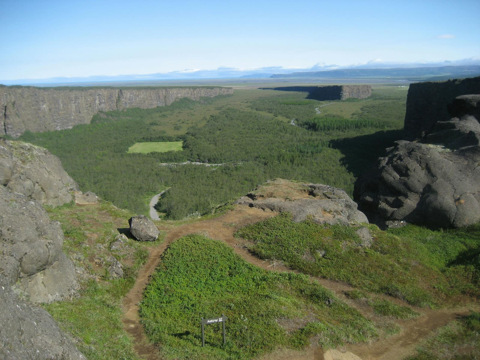 Wide view over Ásbyrgi canyon from Klappir with green woodland between high rock walls.