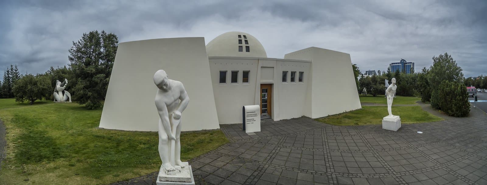 Ásmundarsafn seen from the sculpture garden with white statues and the domed museum building.