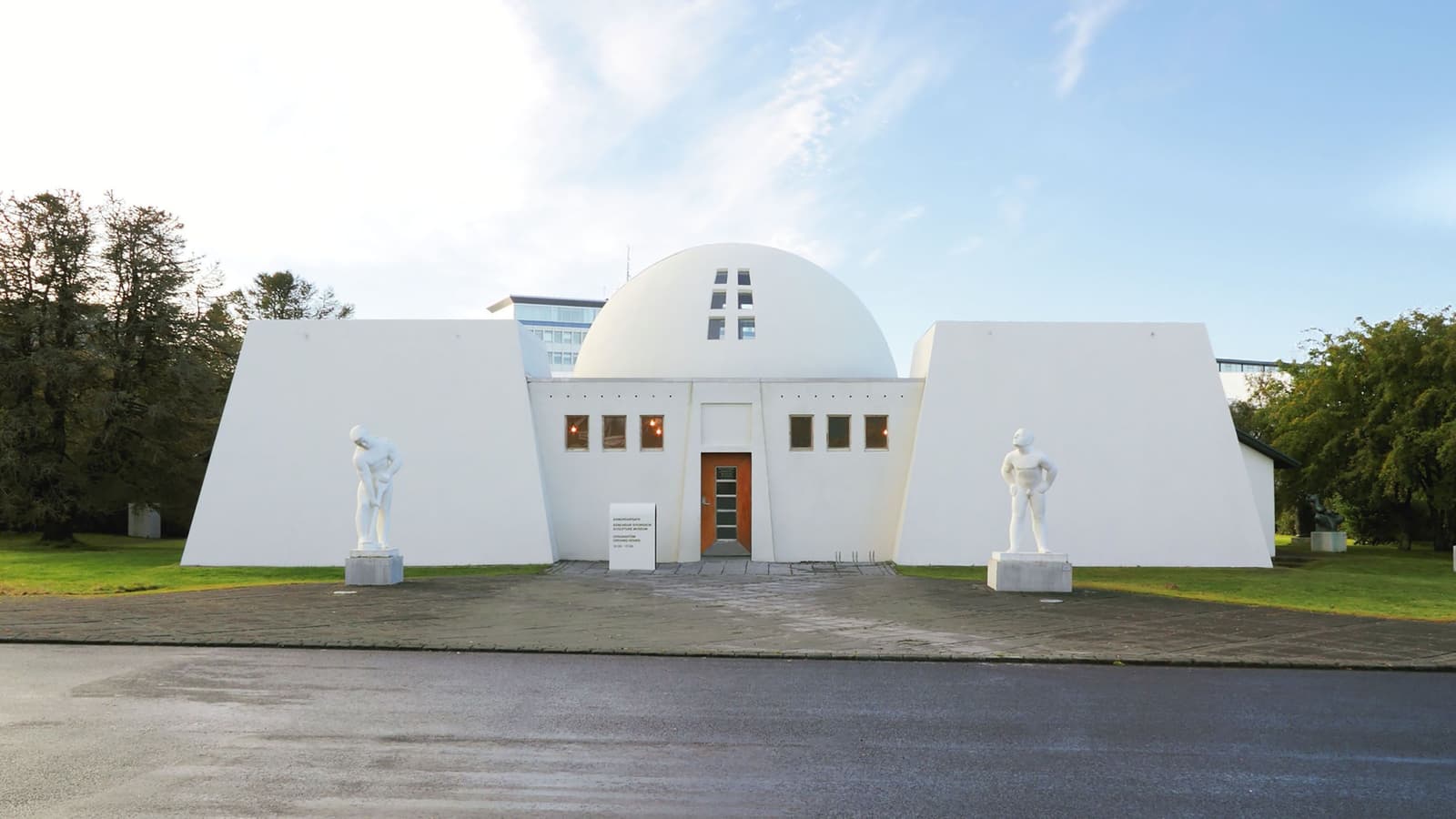 White domed Ásmundarsafn building with Ásmundur Sveinsson sculptures beside the entrance in Reykjavík.