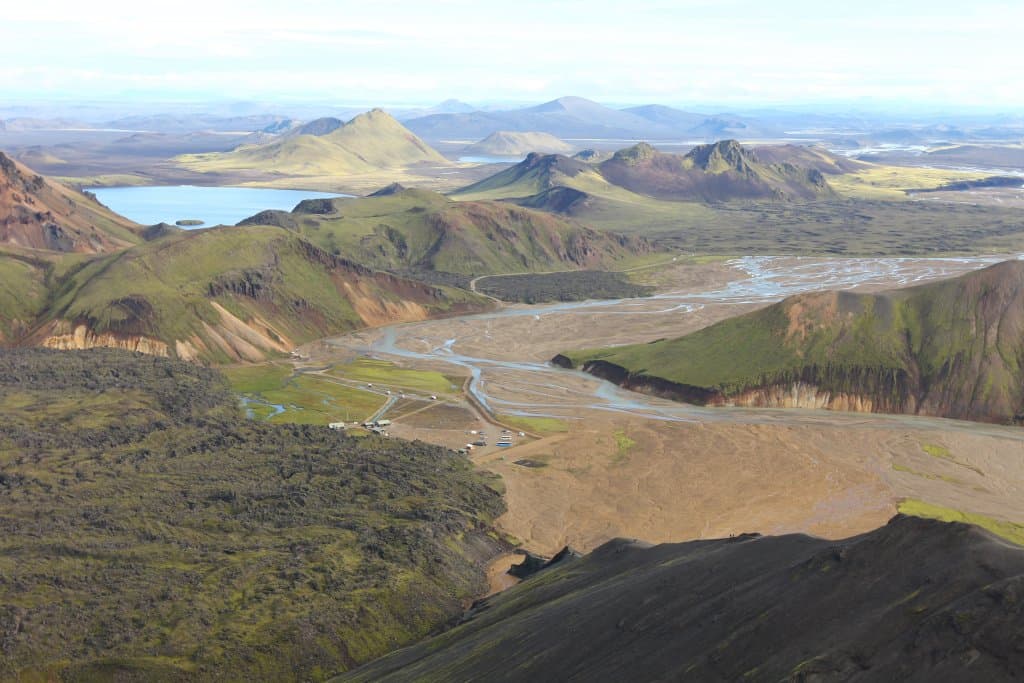 View from Bláhnjúkur over Landmannalaugar, Laugahraun lava, pale river braids, and surrounding Highlands mountains.