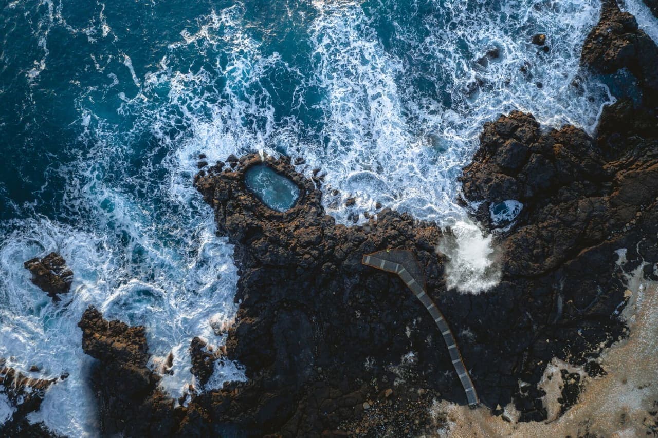 Aerial view of waves surrounding Brimketill lava pool and its viewing platform on the Reykjanes coast.