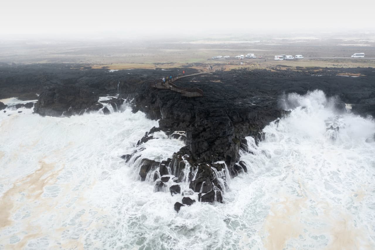 Heavy surf breaking around the Brimketill viewing platform on the black lava coast.