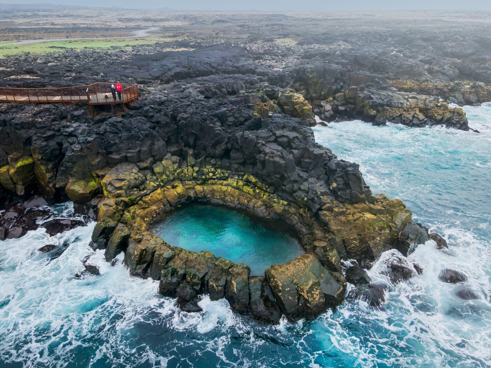 Aerial view of Brimketill with its lava rock pool, viewing platform, black shore, and Atlantic surf.