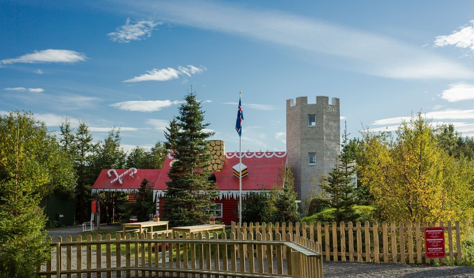 Akureyri Christmas House seen across its fenced garden with the tower and red main building behind it