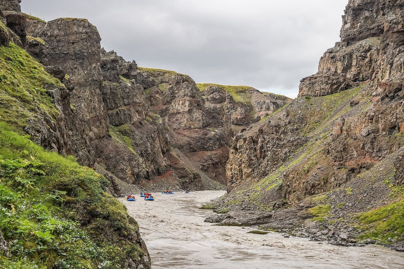 Rafts moving through the Austari-Jökulsá canyon between steep dark rock walls in Skagafjörður.