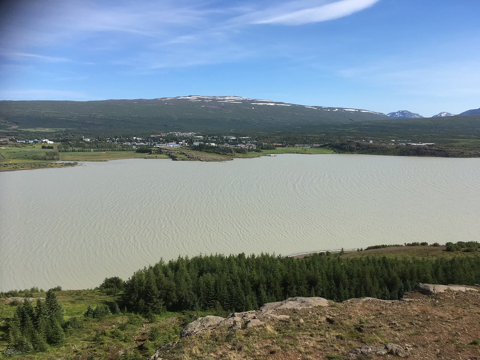 Egilsstaðir beside Lagarfljót with green hills and mountains behind the East Iceland town.