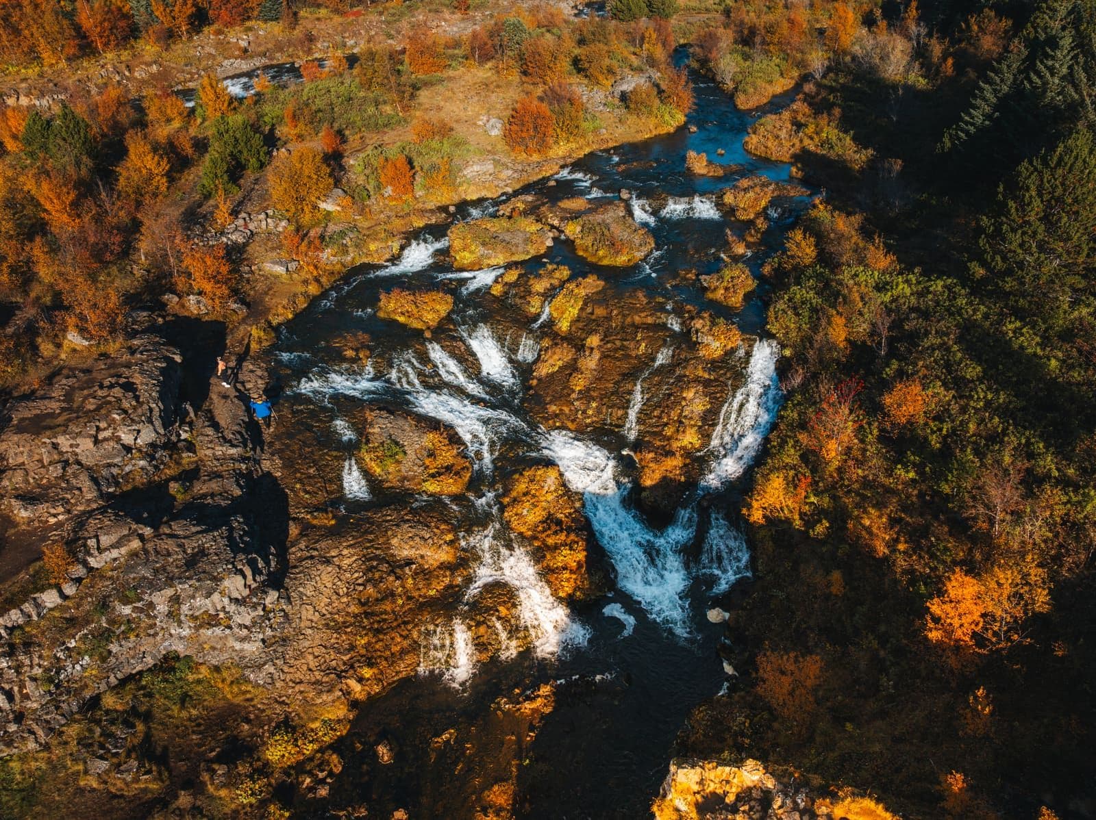 Aerial view of Elliðaá waterfalls and autumn trees in Elliðaárdalur in Reykjavík.