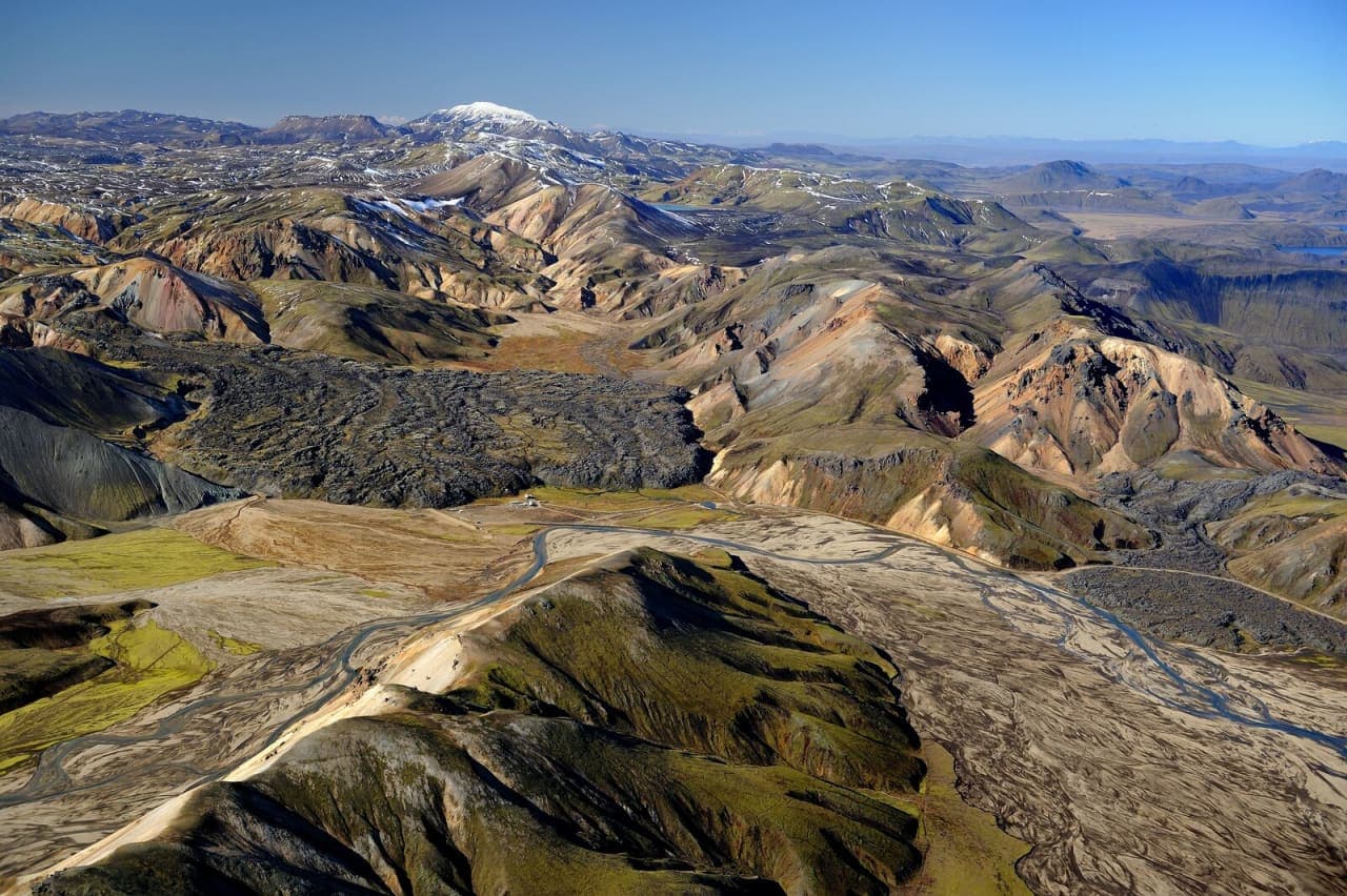 Aerial view of Fjallabak Nature Reserve with colorful mountains, black lava, braided rivers, and Torfajokull in the distance.