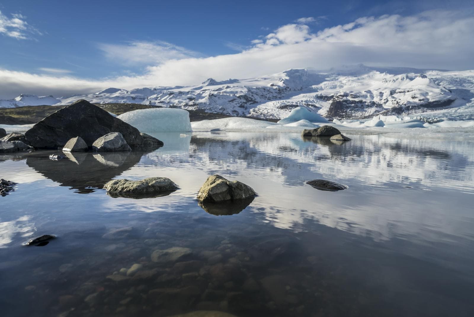 Icebergs and calm water at Fjallsárlón Glacier Lagoon with the Vatnajökull ice behind them.