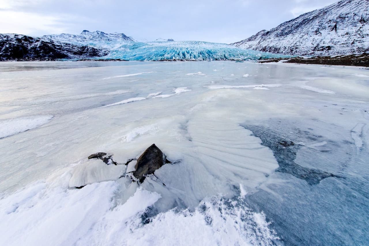 Frozen lagoon surface leading toward the blue front of Fláajökull glacier.
