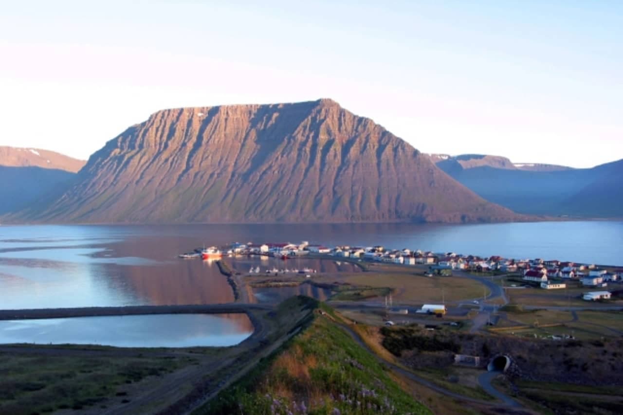 Flateyri village and harbor seen across Önundarfjörður below a broad flat-topped Westfjords mountain.