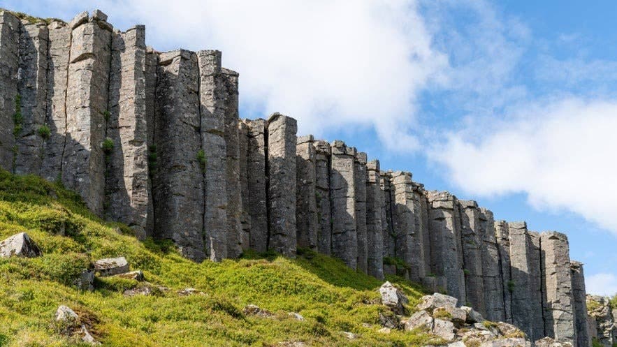Tall hexagonal basalt columns at Gerðuberg rising above a grassy slope on Snæfellsnes.