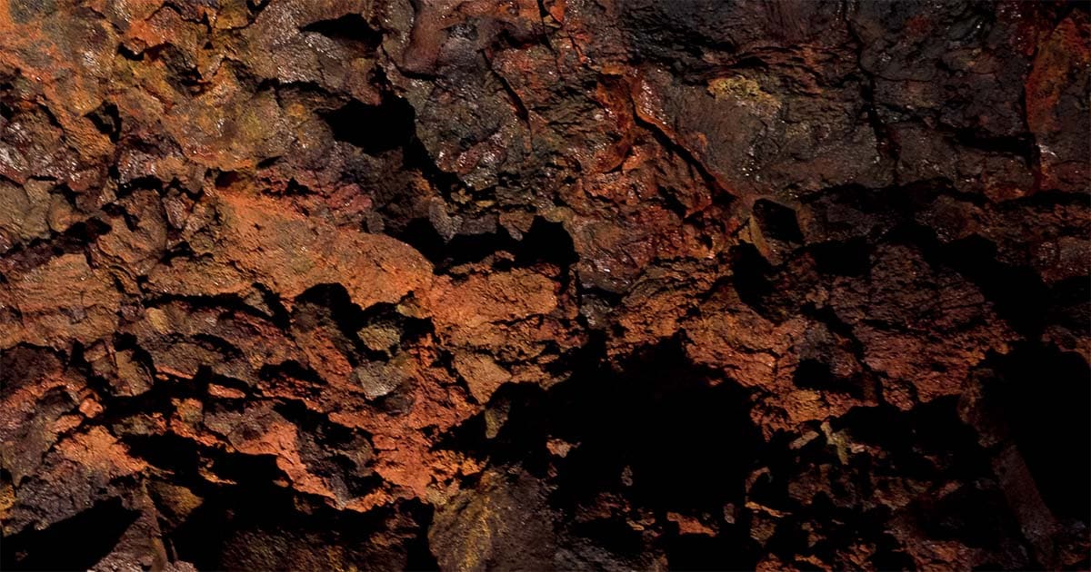 Red and black lava rock texture inside Gjábakkahellir lava tube.