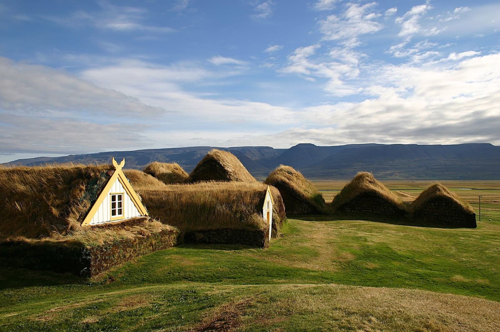Turf-roofed buildings at Glaumbær Museum with Skagafjörður mountains behind them.