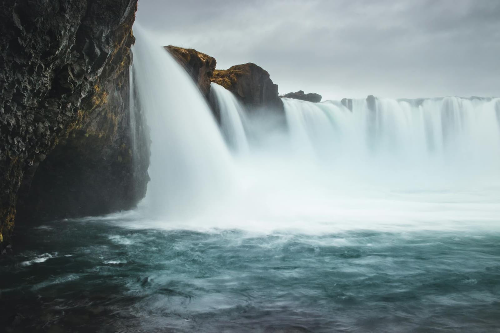 Close view of Goðafoss dropping over dark rock into a misty basin