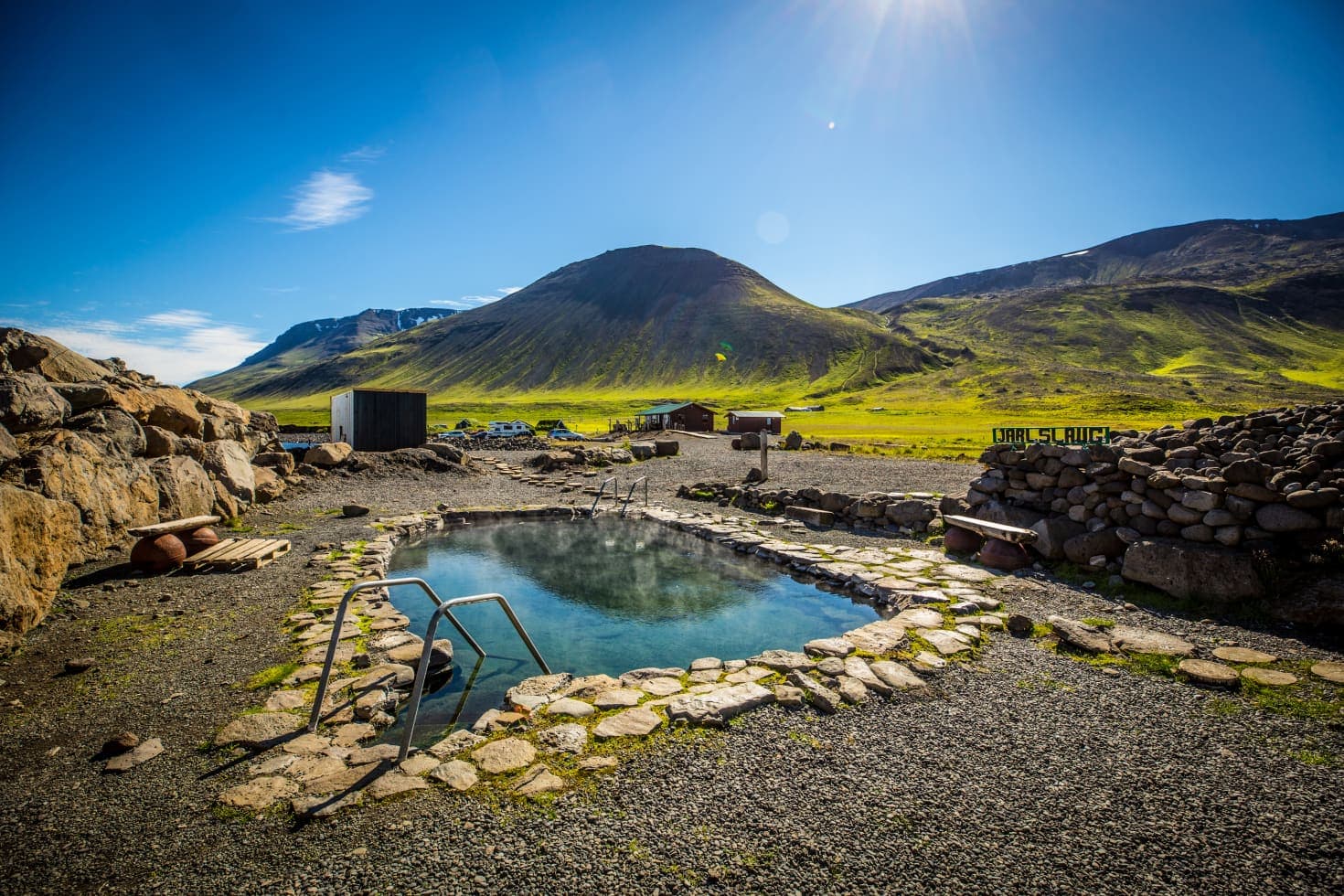 Stone hot spring pool at Grettislaug with Reykjaströnd mountains behind it.
