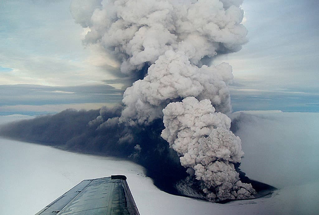 Aerial view of the Grímsvötn eruption plume rising through Vatnajökull ice with an aircraft wing in the foreground.