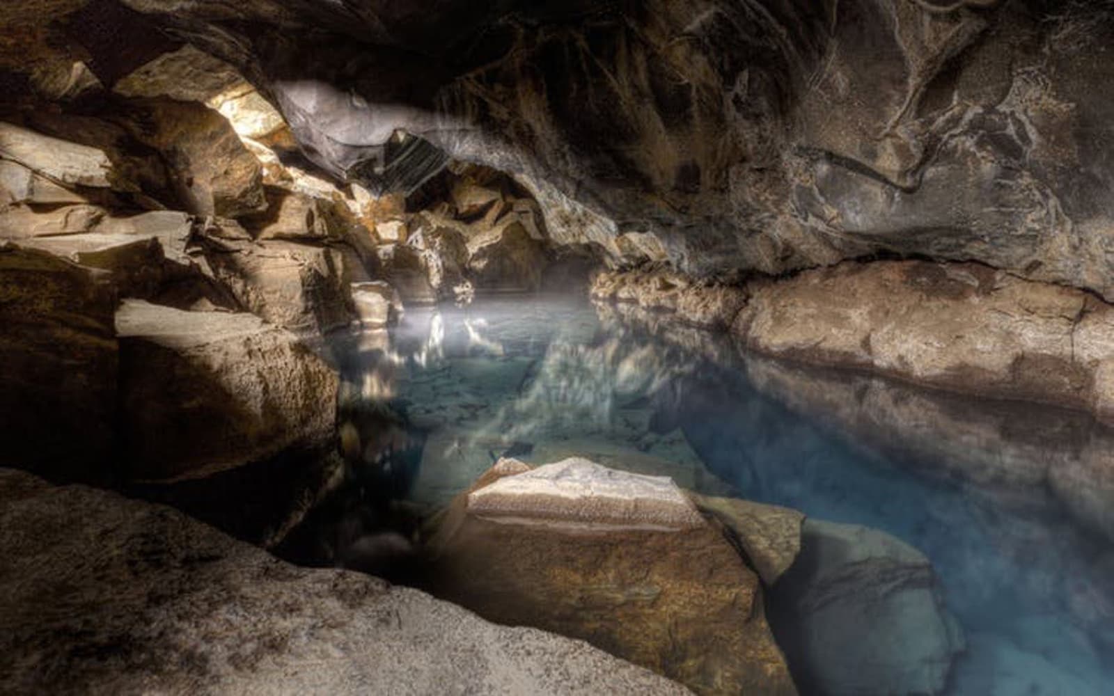 Blue water reflecting the lava ceiling inside Grjótagjá cave in North Iceland.