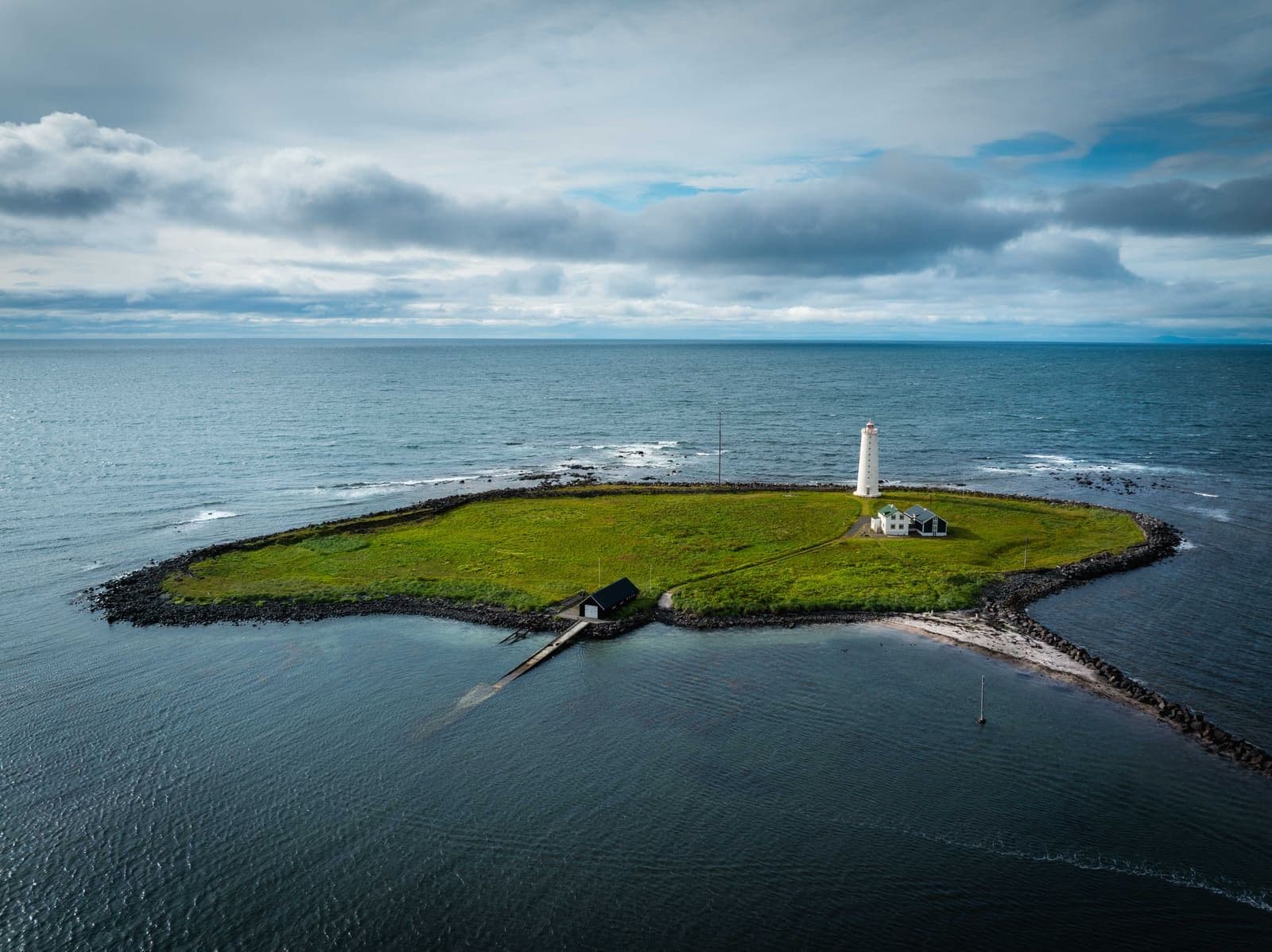 Aerial view of Grótta lighthouse on a small green islet surrounded by sea