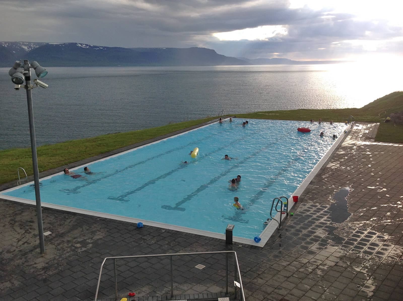 Hofsós swimming pool above Skagafjörður with fjord water and mountains beyond the pool edge.