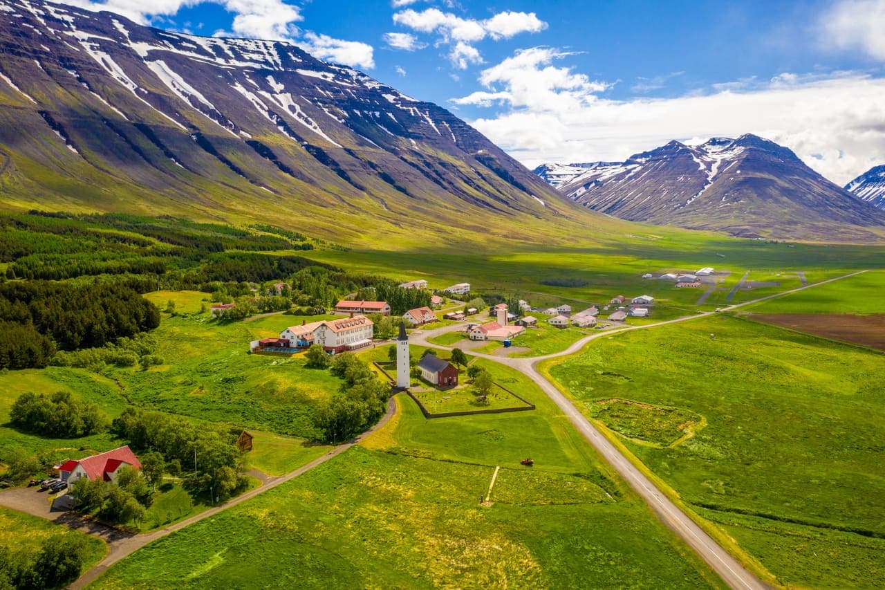 Aerial view of Hólar in Hjaltadalur with the cathedral, school buildings, road, and green valley below Hólabyrða.