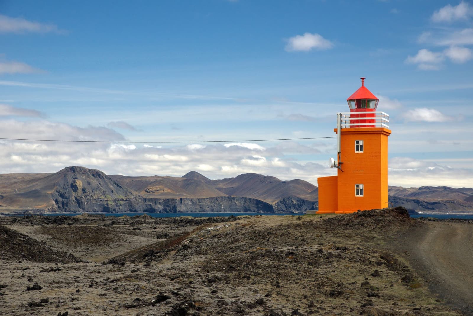 Orange Hópsnesviti lighthouse standing on lava ground above the coast near Grindavík.