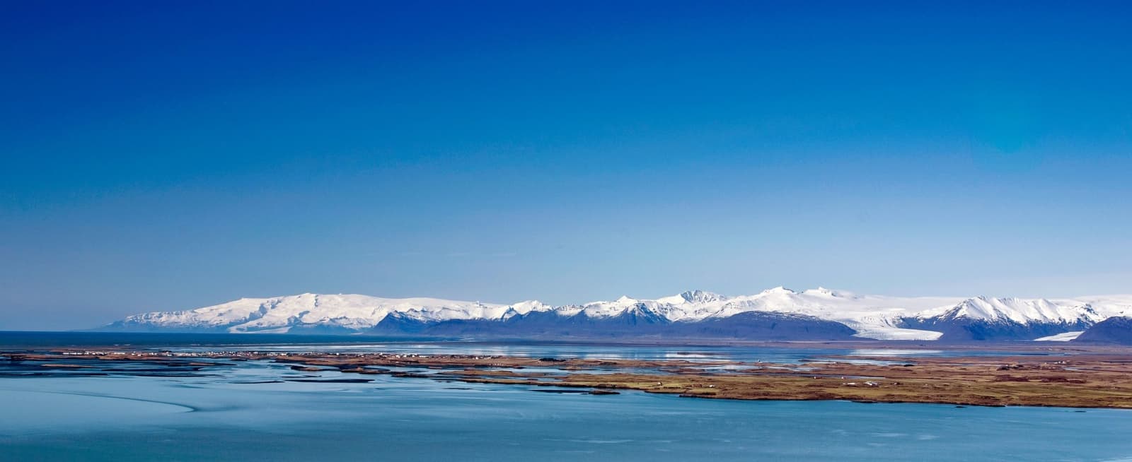 Wide view from Almannaskarð across Hornafjörður toward snowy Vatnajökull mountains.