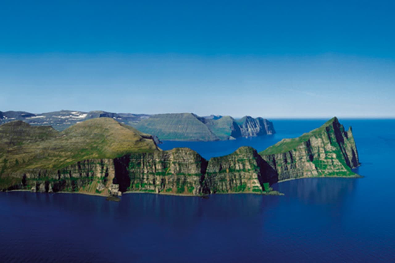 Wide view of the Hornbjarg sea cliffs rising above the water in Hornstrandir.