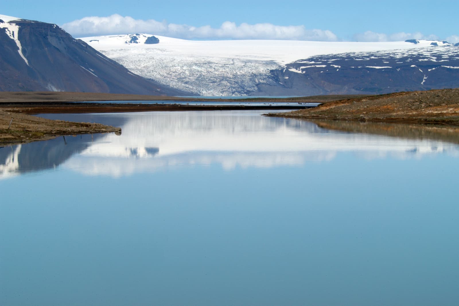 Hvítárvatn lake reflecting Langjökull glacier and bare highland slopes.