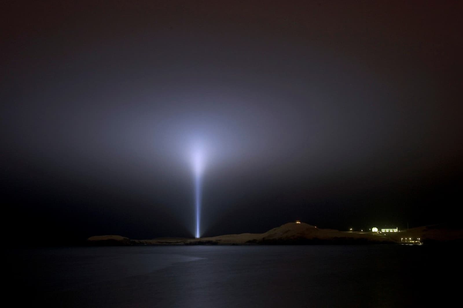 Imagine Peace Tower beam shining from Viðey across the dark bay