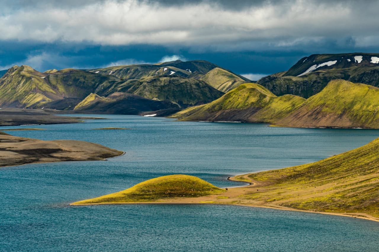 Langisjór lake winding between green volcanic mountains under low Highlands cloud.