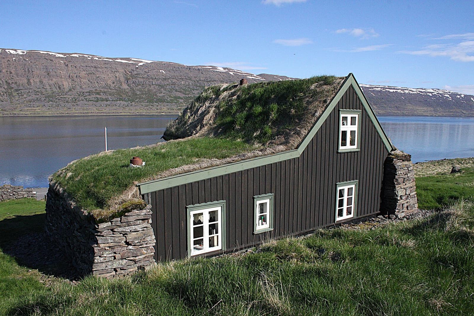 Litlibær turf-roof farmstead in Skötufjörður with Westfjords mountains behind.