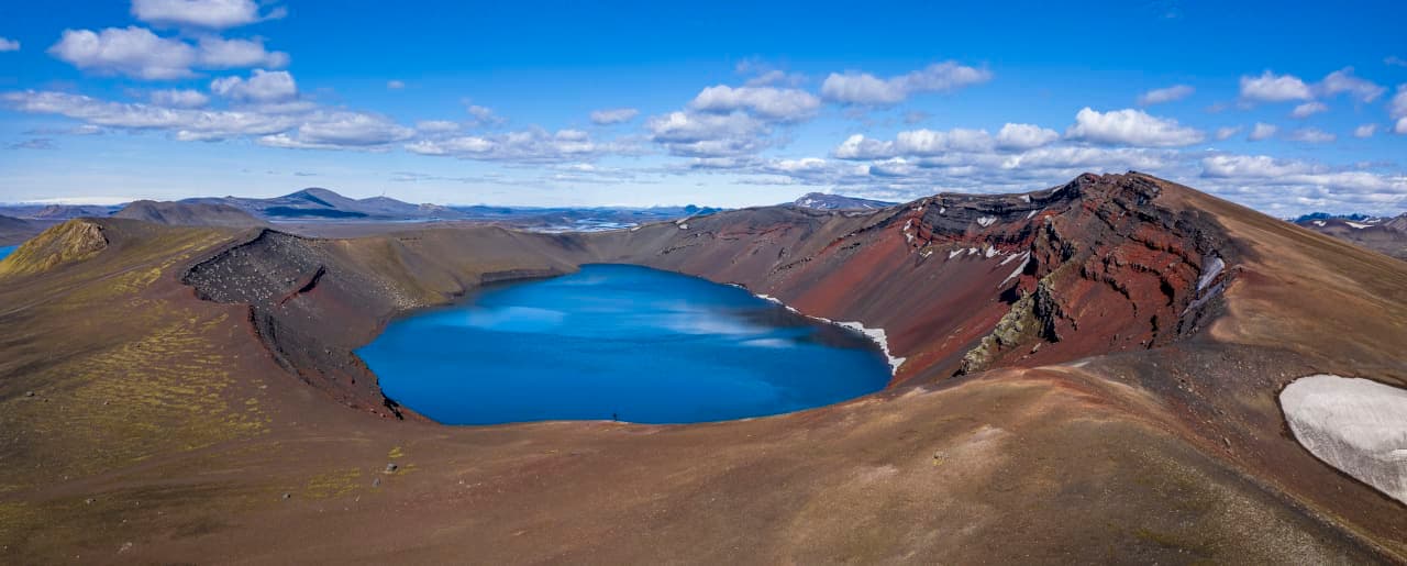 Blue Ljótipollur crater lake surrounded by red and brown volcanic slopes in the South Highlands.