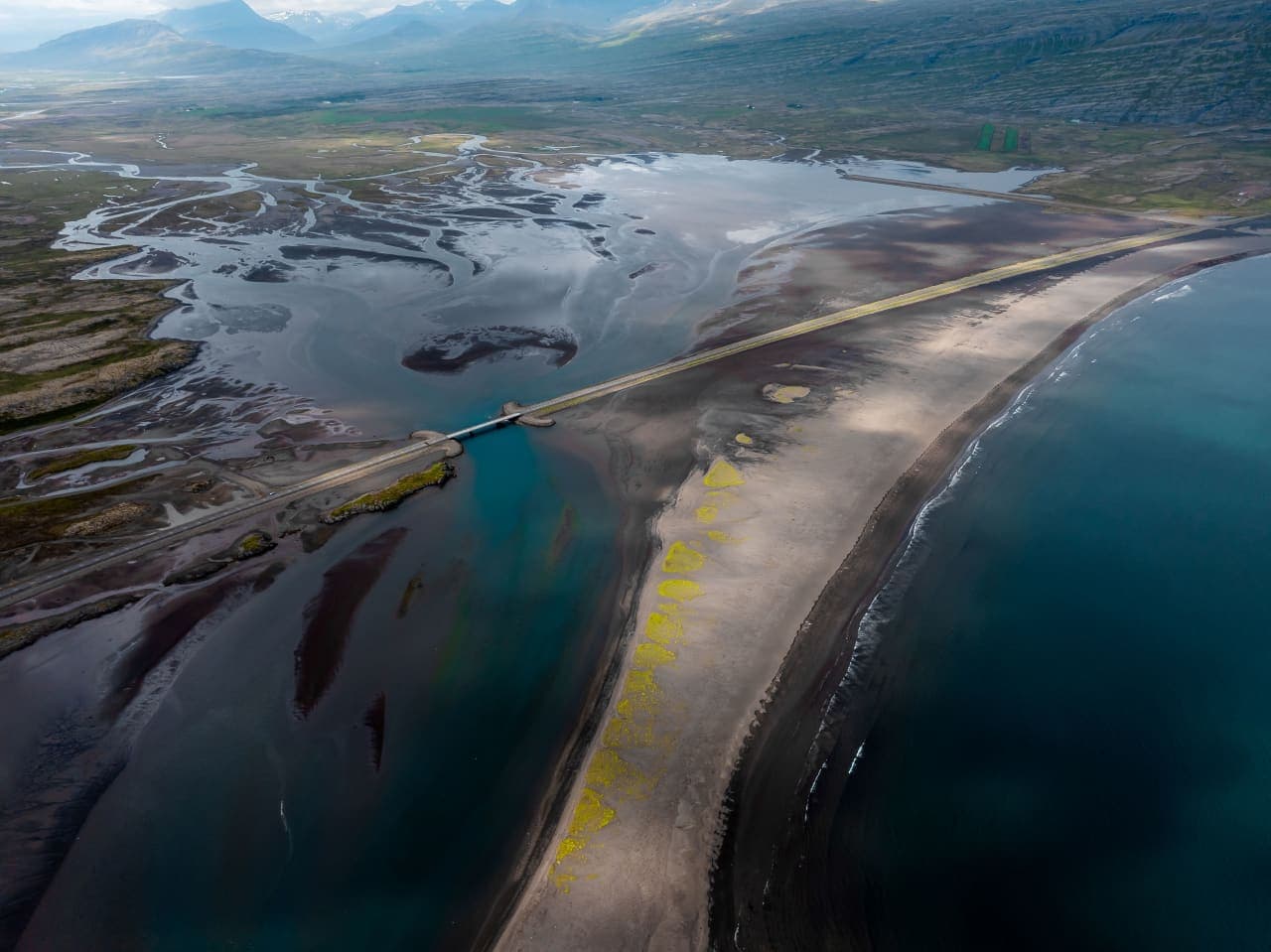 Aerial view of Meleyri Beach, the lagoon, and the road across the black-sand spit by Breiðdalsvík.