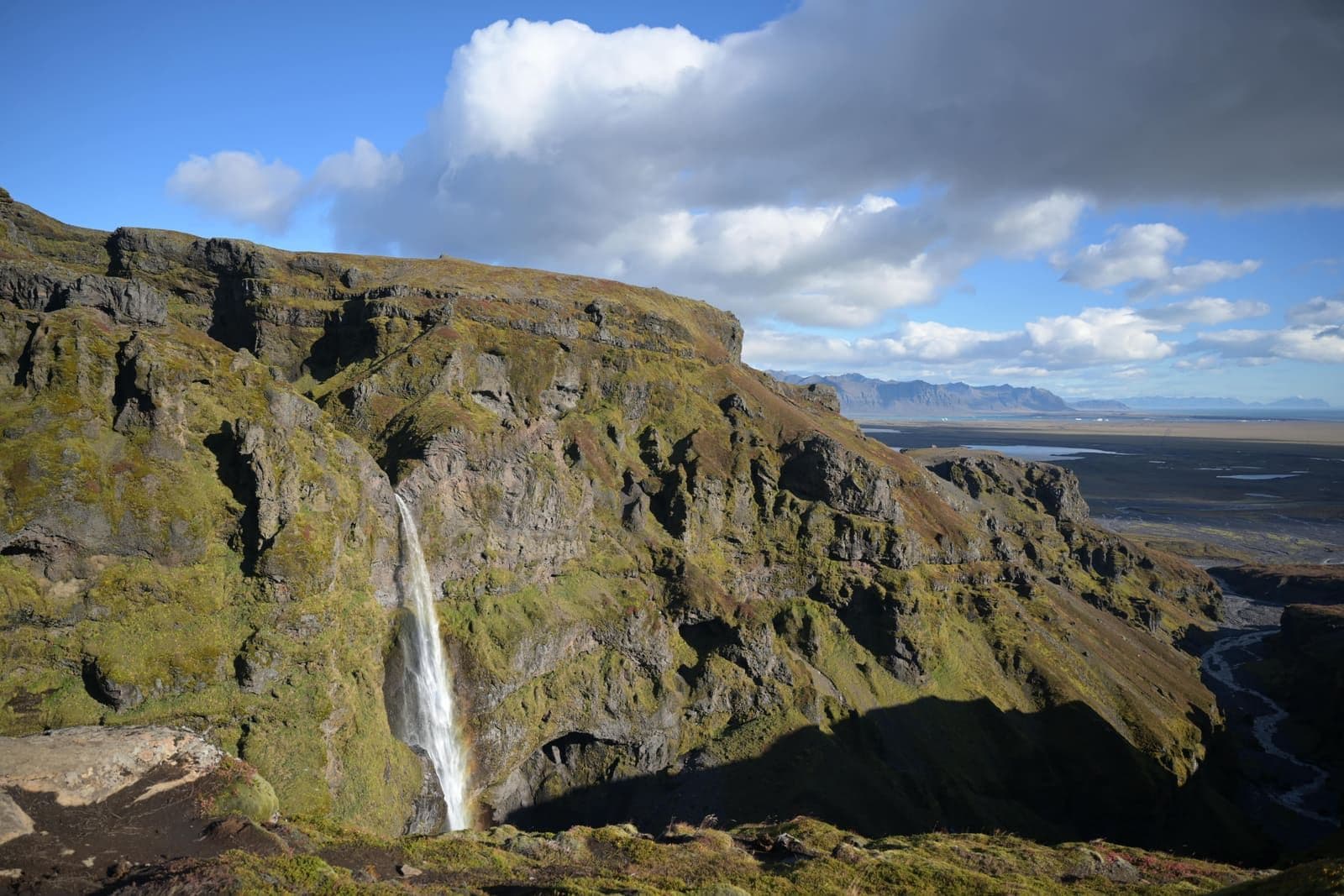 Hangandifoss plunging into Múlagljúfur Canyon with steep mossy cliffs around the falls.