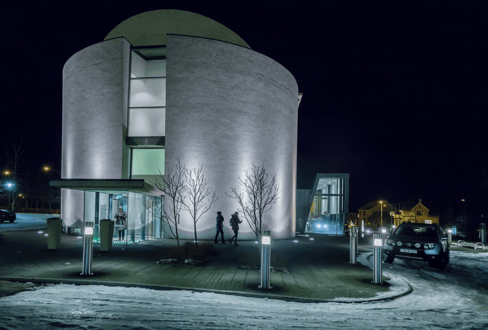 National Museum of Iceland entrance lit at night with snow along the Reykjavík pavement.