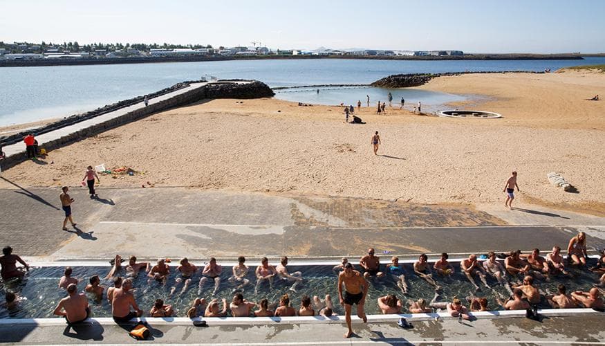 People bathing beside the sandy cove at Nauthólsvík geothermal beach in Reykjavík