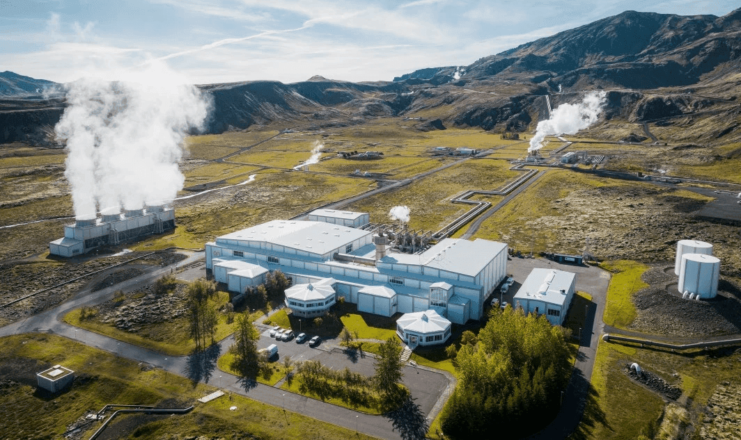 Aerial view of Nesjavallavirkjun with steam rising from geothermal pipes in the Hengill landscape.